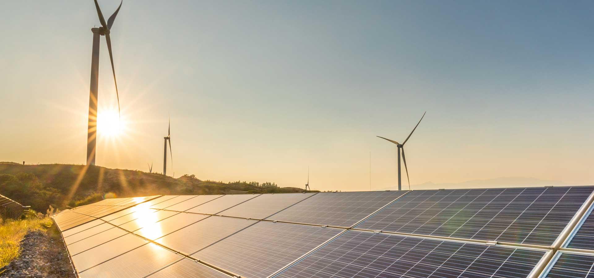 Wind turbines and solar panels in a renewable energy field at sunset